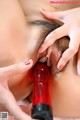 A woman is holding a red dildo in her mouth.