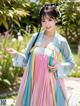 A woman in a blue and pink hanbok is posing for a picture.