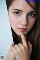 A close up of a woman's face with her finger on her lips.