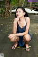 A woman in a blue dress sitting on a wooden floor.