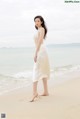 A woman in a white dress standing on a beach.