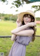 A woman in a purple dress and a straw hat posing for a picture.