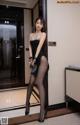 A woman in a black dress and black stockings posing for the camera.