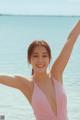 A woman in a pink bathing suit standing in the ocean.