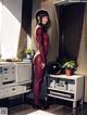 A woman in a red bodysuit standing in a room.