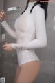 A woman in a white bodysuit holding a shower head.